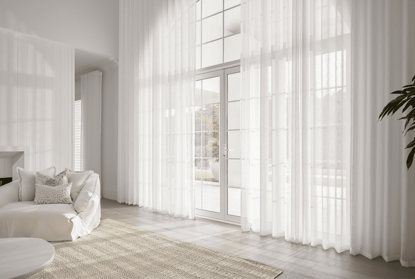 A stunning living space featuring elegant sheer curtains in Adelaide by Betta Blinds, with floor-to-ceiling sheer block curtains that filter natural light and add a touch of luxury.